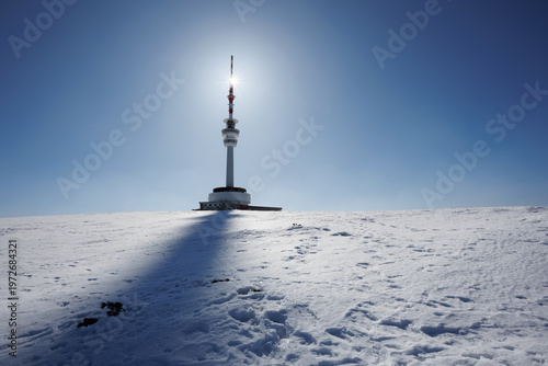 Television and communications tower and transmitter, Praded, Jeseniky mountains, Czech Republic, Czechia. Tall utility building on the top of the mountain and hill. Sun and backlight in the winter.