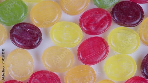 Colorful candy closeup. Vivid multicolor candies with glossy surfaces. Detailed macro shot showcasing colorful candies against smooth white surface with shiny highlights