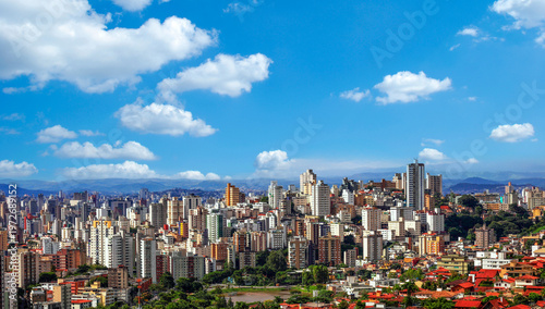 Obraz na płótnie Vista panorâmica da vibrante região Centro-Sul de Belo Horizonte, Brasil, exibindo um horizonte denso de edifícios coloridos contra um pano de fundo de montanhas onduladas e um céu azul brilhante