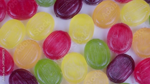 Closeup of vibrant candies scattered across plain white backdrop for packaging. Brightly colored confections in macro view with seamless pattern suitable for promotional designs