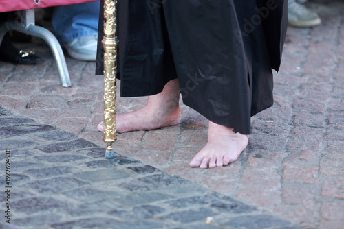 Foto Barefoot Holy Week penitent with gilded staff on cobblestones in Madrid, Spain