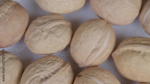 Walnut shells arrangement. Macro photography highlighting beige tones and rough textures of whole walnut shells arranged systematically on white surface for organic food themes