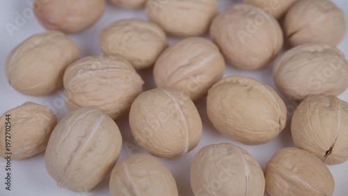 Scattered beige walnuts emphasizing ridged textures and neutral tones. Detailed view of beige walnuts on white with soft lighting and minimal composition for various uses