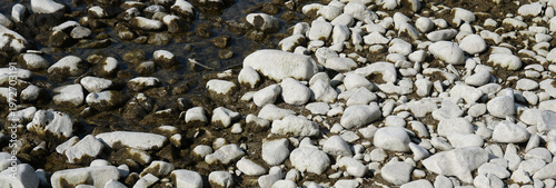 Tableau sur toile Weiße Bollensteine in einem teilweise ausgetrockneten Flussbett mit wenig Wasser