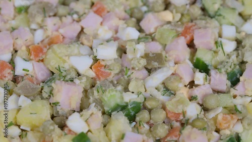Salad with colorful ingredients. Vivid potato and ham mix. Closeup of vibrant egg and vegetable salad. Macro shot showcasing textured mix of vegetables and meats in salad
