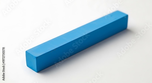 A bright blue rectangular chalk stick lies diagonally on a white surface, with soft lighting