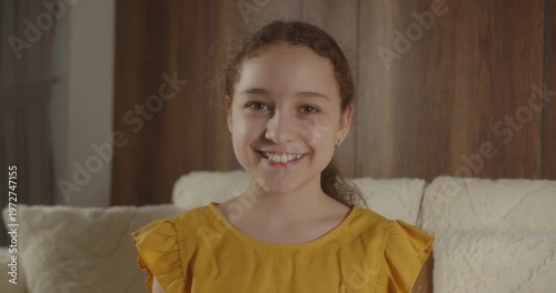 Portrait of smiling 12 year old girl sitting on sofa at home.