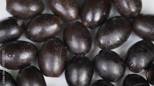Highquality olives with glossy oil droplets reveal detailed texture. Closeup of shimmering black olives highlighting texture and rich tones used for gourmet dishes