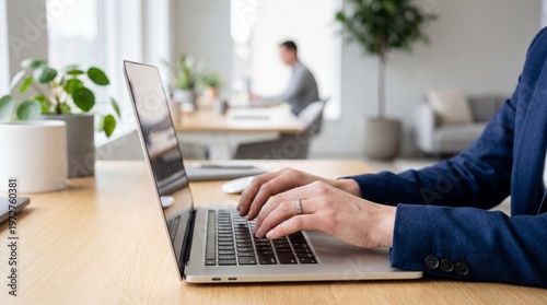 Business professional typing on laptop within bright modern office space