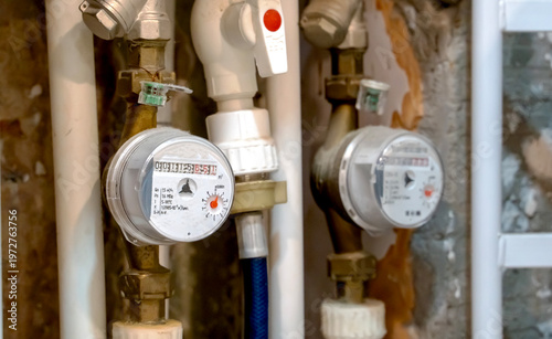 Water meters mounted beside pipes in a utility space
