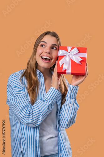 Happy Grateful Woman With Gift Box On Beige Wall. Lady Smiling,Present, Surprise