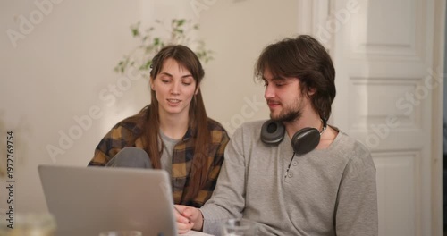 Young couple share joyful moments while working on a laptop, surrounded by a cozy atmosphere and warm lights