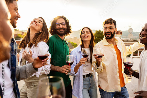 Foto Happy smiling friends enjoying a rooftop party with wine, toasting and laughing