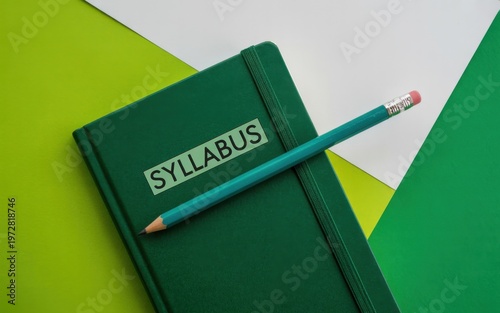 A green notebook with a syllabus and pencil on colorful background