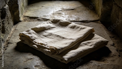 Empty grave clothes folded inside a dim tomb on stone surface