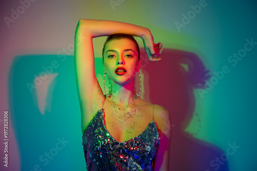 Wallpaper Mural Beautiful young woman with perfect skin and colourful makeup in neon studio light poses in silver sparkle party dress. Portrait of beauty model with makeup and long eyelashes. Selective focus. Torontodigital.ca