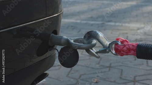 Hand attaching tow rope hook to a car for recovery