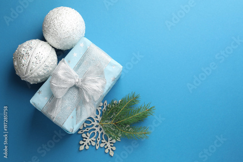 Christmas balls, gift, snowflake and fir tree branch on light blue background, flat lay. Space for text