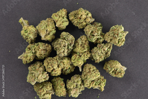 Several dried cannabis buds arranged on a dark surface.