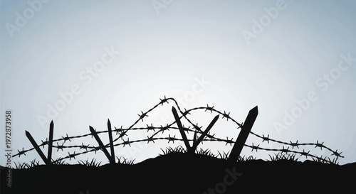 Black silhouette of protective barbed wire fence with sharp spikes and wooden stakes on a ground mound with grass blades against a clear gradient sky background.