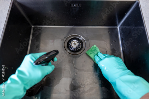 Stockholm, Sweden A dirty sink is cleaned by with a sponge and rubber gloves.