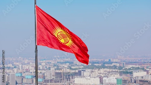 Kyrgyz National Flag Billowing in Air - orbiting close drone view with Bishkek city in the background