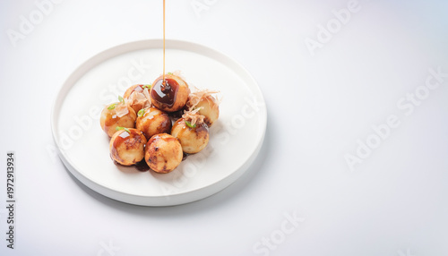 Takoyaki on a plate with sauce being drizzled. ideal for food blogs, restaurant menus, asian cuisine articles.