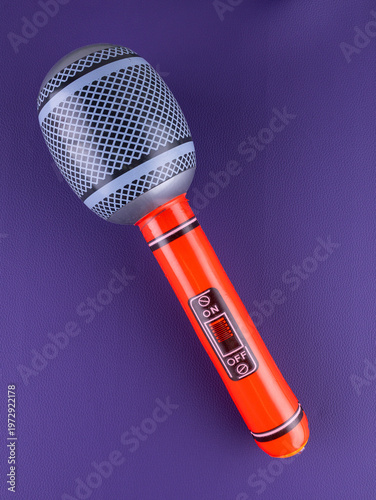 Close-up of a fun red inflatable microphone toy for entertainment on a purple background.