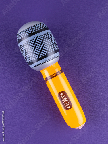 Close-up of a fun orange  inflatable microphone toy for entertainment on a purple background.