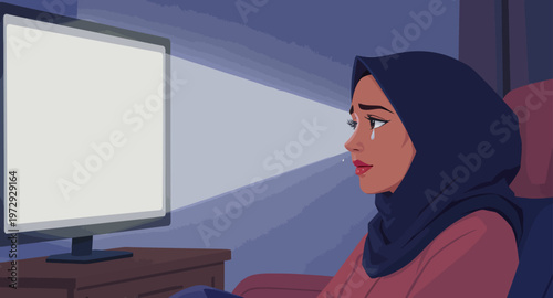 Woman wearing hijab sitting in front of computer screen.