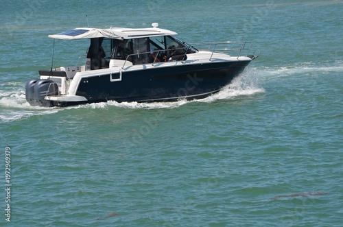 Black with white trim motorboat powered by two outboard engines cruising on the Florida Intracoastal Waterway near Miami Beach.