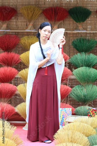 Vietnamese model in a red and white dress in front of a traditional display. 