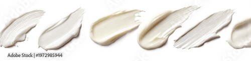 Swatches of cosmetic creams and lotions in various shades of white and beige on a white background.