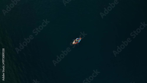 Fishing boat with crew navigating through calm waters, showcasing the serene environment and the rhythmic motion of oars against the water surface
