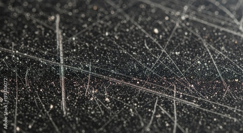 Close-up view of a heavily scratched dark surface covered in fine white dust and intricate linear marks.