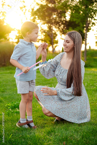 mom and child playing on a green lawn in the park in the summer, having fun together, mother and small child walking in the summer, playing on the grass