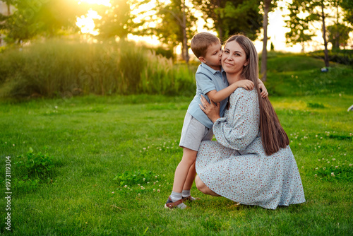 mom and child playing on a green lawn in the park in the summer, having fun together, mother and small child walking in the summer, playing on the grass