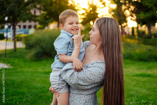 mom and child playing on a green lawn in the park in the summer, having fun together, mother and small child walking in the summer, playing on the grass