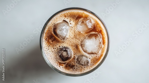 Simple glass of iced coffee with ice cubes and foam on a clean white backdrop