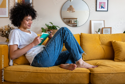 Woman relaxing at home, enjoying book on sofa