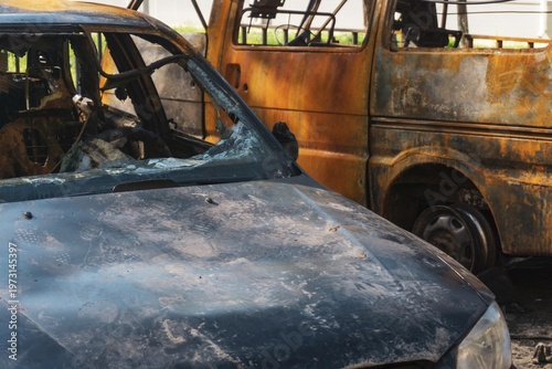 Obraz na plátne Burnt van with heavy rust and missing windows parked on a dirt patch near a residential building and trees