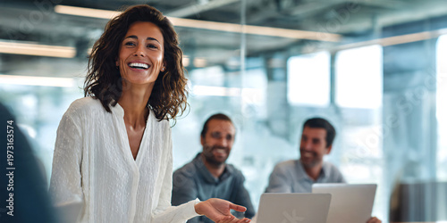 Group of business professionals in modern boardroom meeting, female team leader standing and presenting ideas on whiteboard.