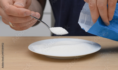Foto White loose sugar crystals close-up on a spoon, sweetened