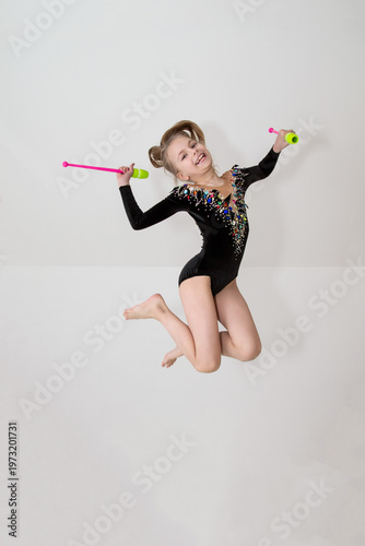 A young rhythmic gymnast in a beautiful velvet black leotard is training.