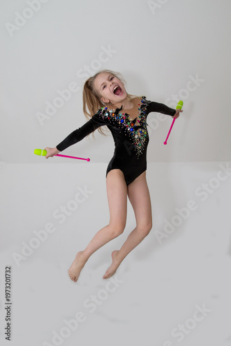 A young rhythmic gymnast in a beautiful velvet black leotard is training.