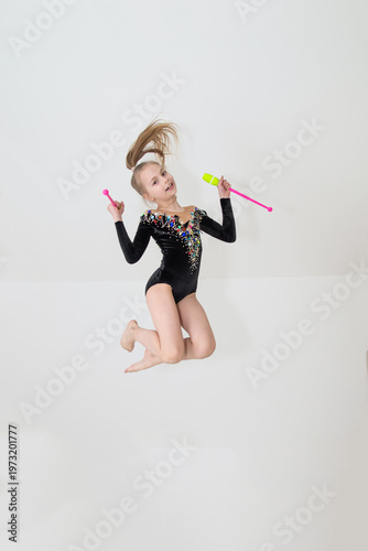 A young rhythmic gymnast in a beautiful velvet black leotard is training.