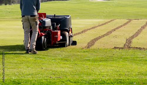 Slika na platnu Groundskeeper aerating golf course green with professional turf maintenance mach