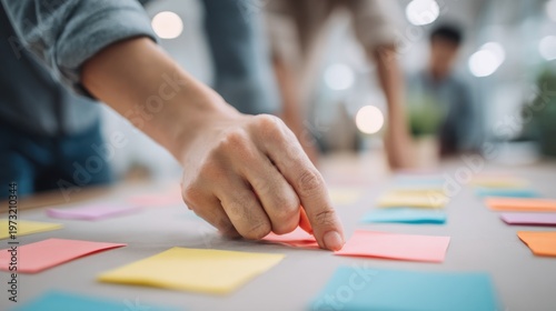 Diverse team collaborates on sticky note strategy session, organizing ideas on a large table for planning and brainstorming.