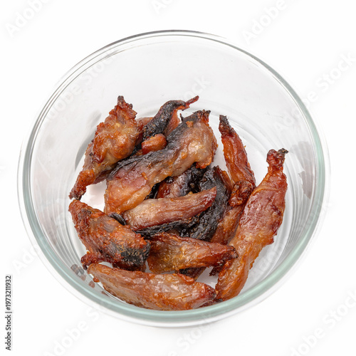 Fried Thai sun-dried Longtail Tuna or Euthynnus affine slices in a glass bowl isolated on white background, selective focus on delicious salty fish for authentic Asian cuisine concept.