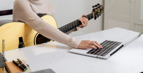 Foto Woman musician holding acoustic guitar and using laptop